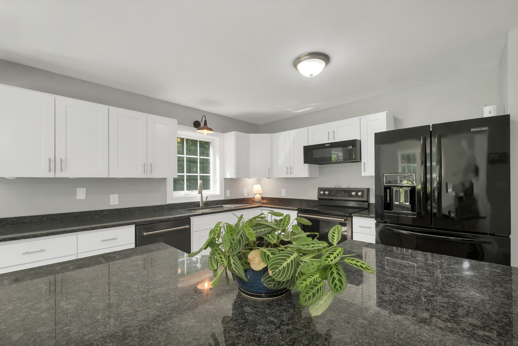 Updated kitchen with white cabinets, granite counters, and a peninsula