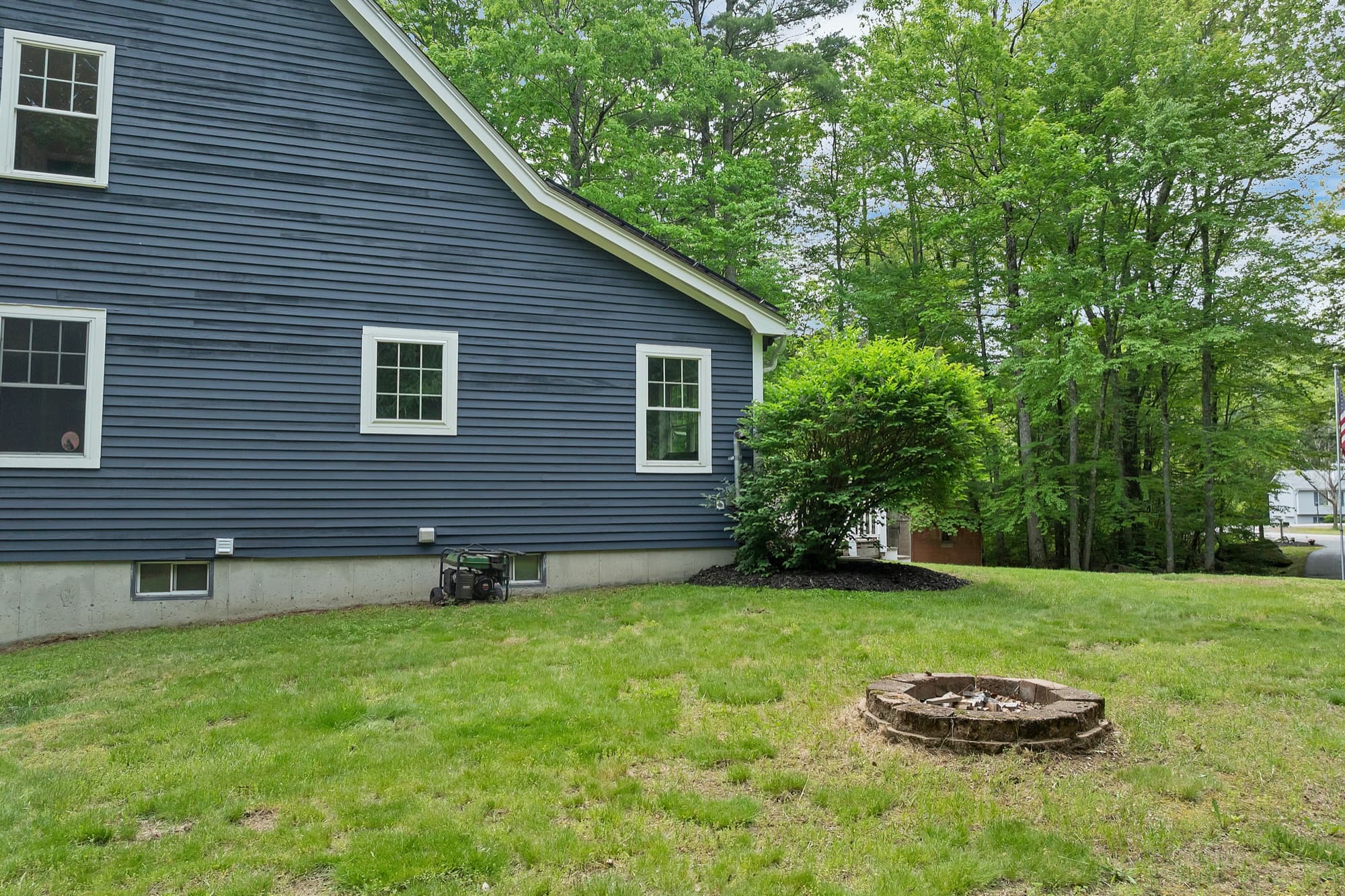 Rear elevation with the stone fire ring in the level back lawn